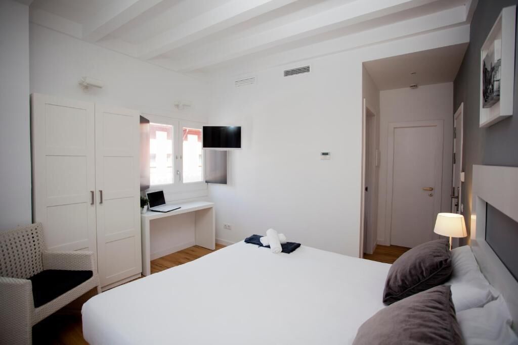 Une chambre à coucher avec un lit, un bureau, une chaise et un téléviseur.