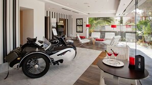 A modern hotel lobby with a classic motorcycle, seating area, and a view of the outdoors. - Hotel Sitges (Sitges)
