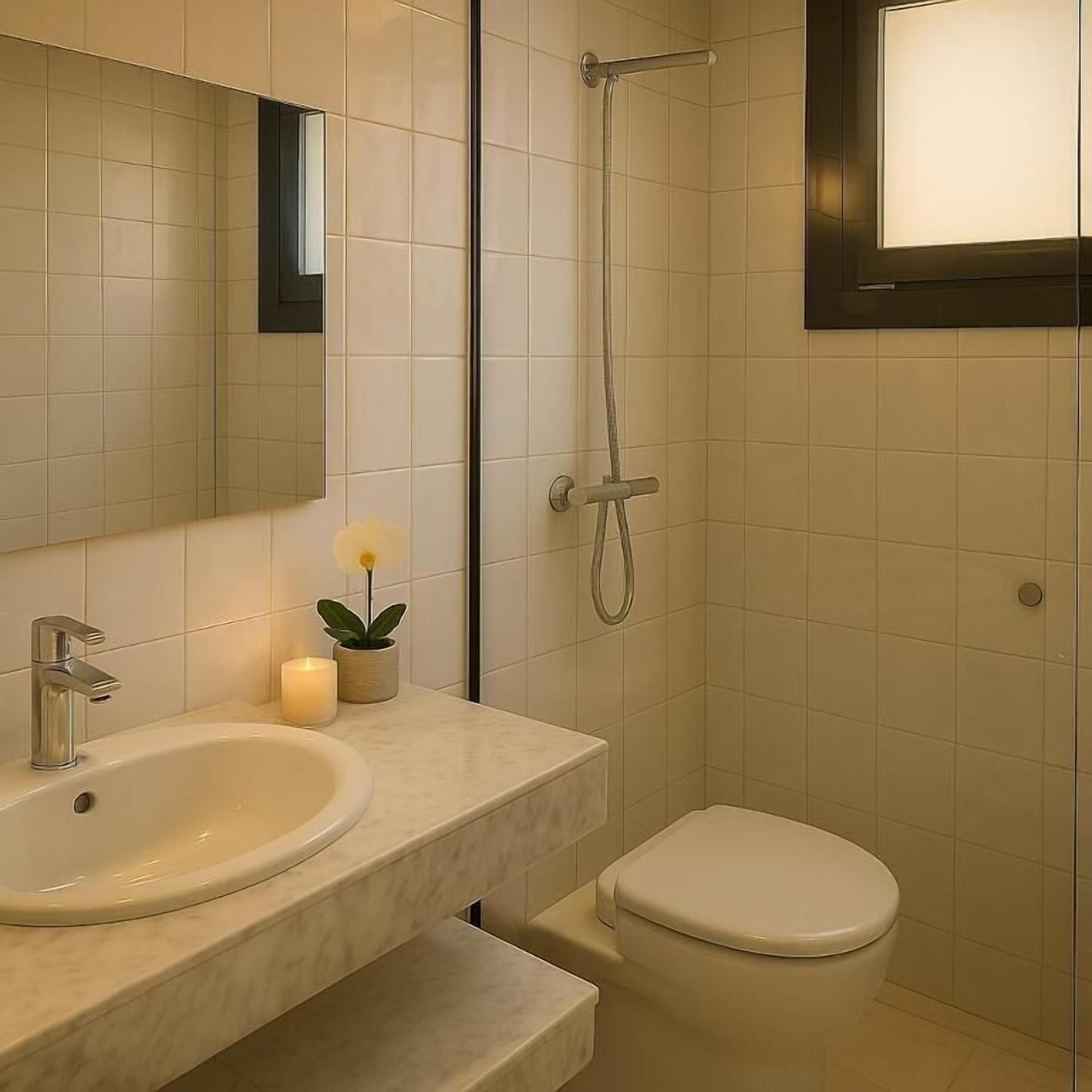 Un baño con lavamanos, espejo, inodoro y ducha.