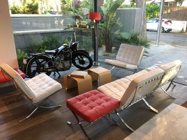 A modern outdoor seating area with cushioned chairs and a motorcycle.