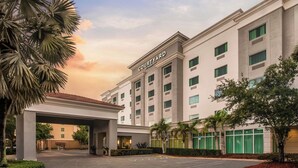 A Courtyard hotel with a covered entrance, palm trees, and a clear sky.