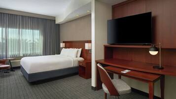 Een hotelkamer met een groot bed, een bureau, een stoel, een flatscreen televisie en een klein tafeltje.