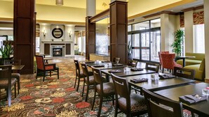 A hotel lobby with a fireplace, dining area, and large windows. - Hilton Garden Inn Pittsburgh/Cranberry (Cranberry Township)