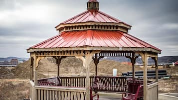 Gazebo amb teulada vermella i estructura de fusta, amb dos bancs vermells i una taula petita.