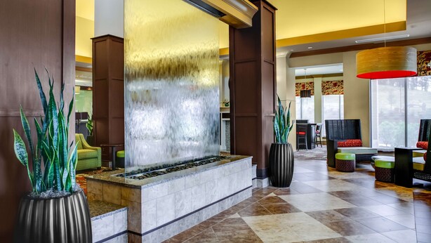 A lobby with a water feature, seating area, and large windows. - Hilton Garden Inn Pittsburgh/Cranberry (Cranberry Township)