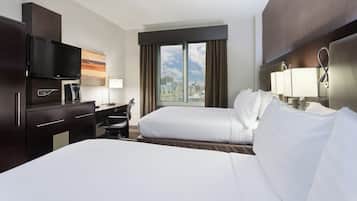 Habitación de hotel con cama, escritorio, silla, televisor y ventana con vista a la ciudad.