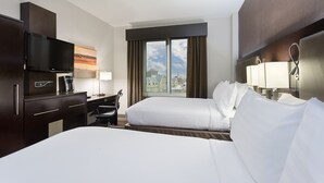 A hotel room with a bed, a desk with a chair, a TV, a lamp, and a window with a city view. - Holiday Inn NYC - Lower East Side by IHG (New York)