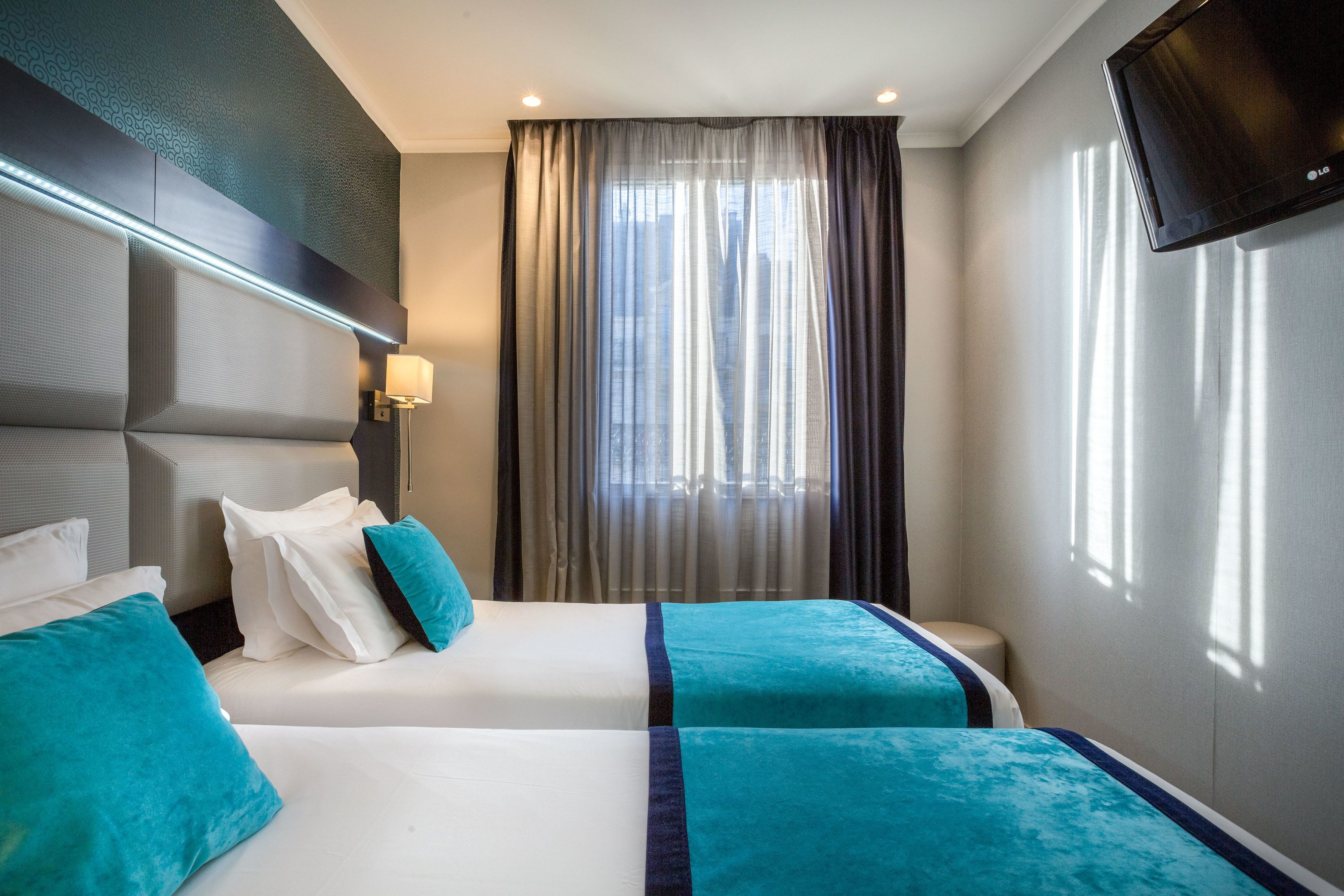 Een hotelkamer met een groot bed, een flatscreen televisie en een raam met gordijnen.