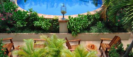 Una piscina rodeada de exuberante vegetación y muebles de madera.