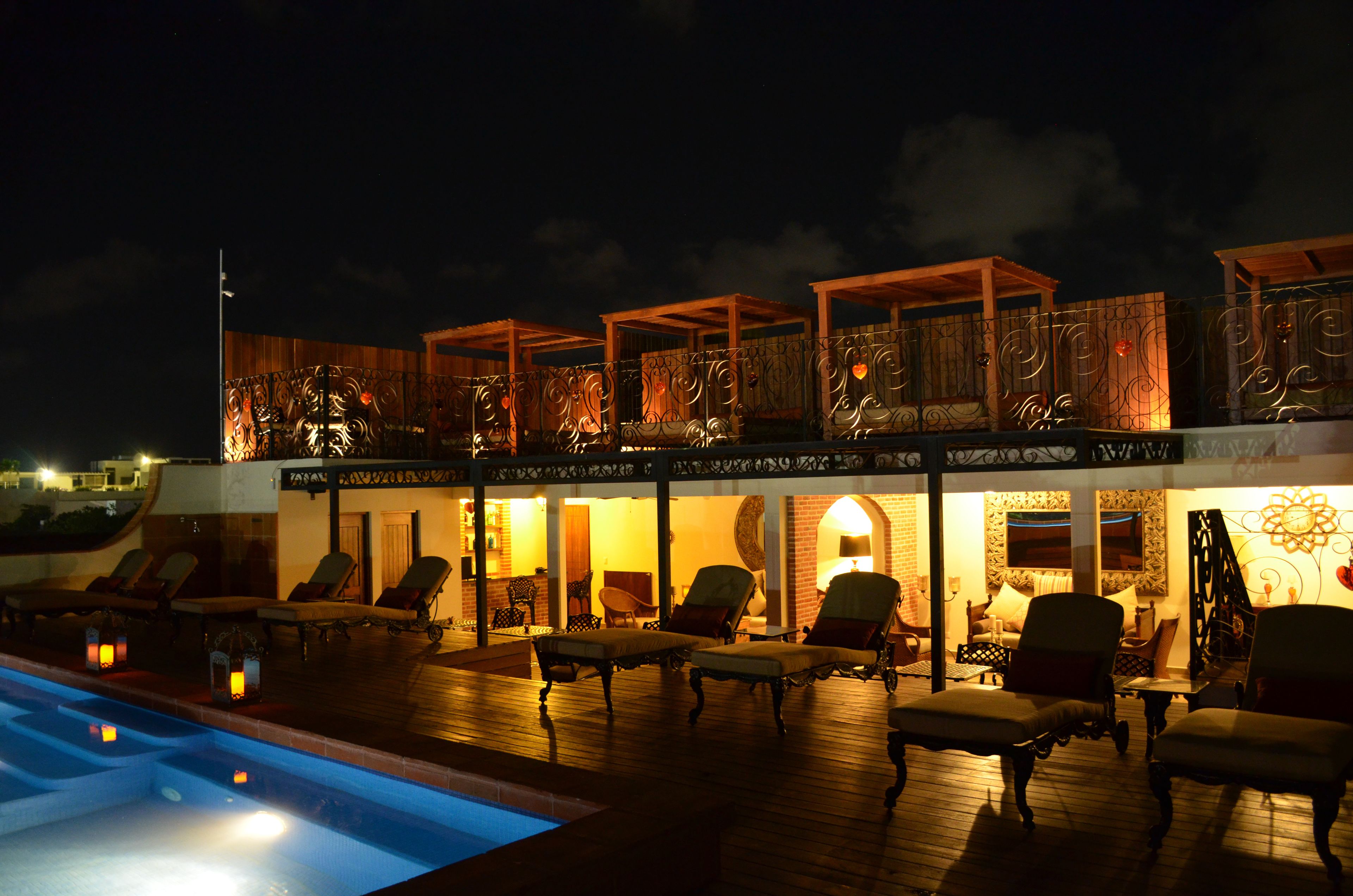 A rooftop pool area with lounge chairs and a wooden deck.