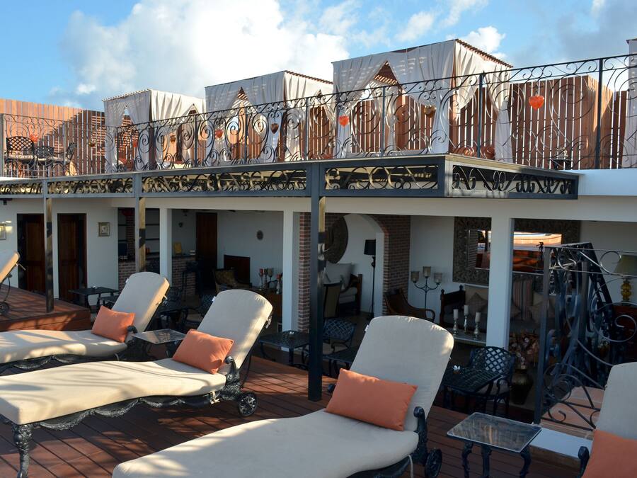 A rooftop lounge area with sun loungers and a covered patio.