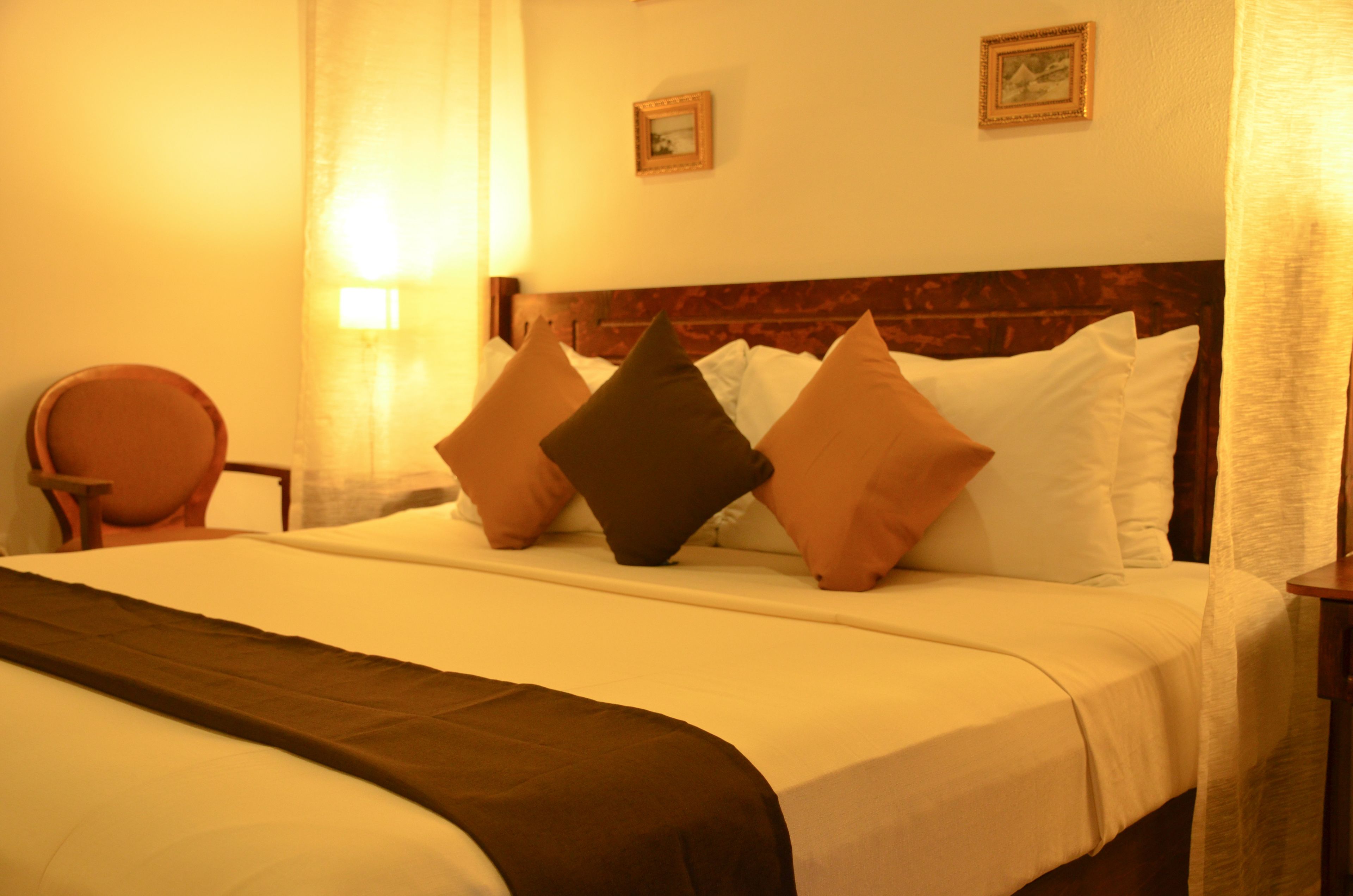 Habitación de hotel con una cama grande, cabecera de madera y dos cuadros enmarcados en la pared.