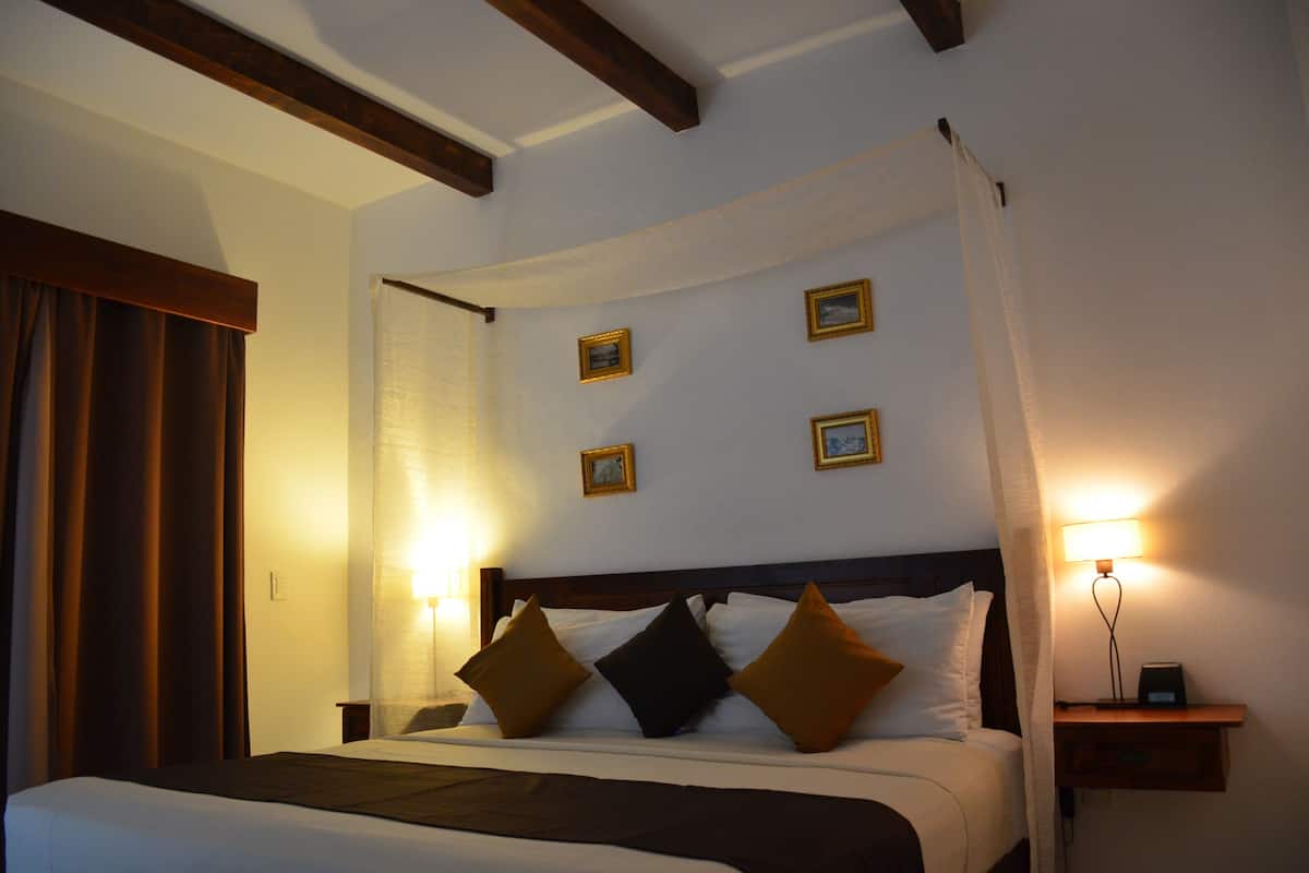 A hotel room with a bed, a nightstand, and a wall-mounted lamp.
