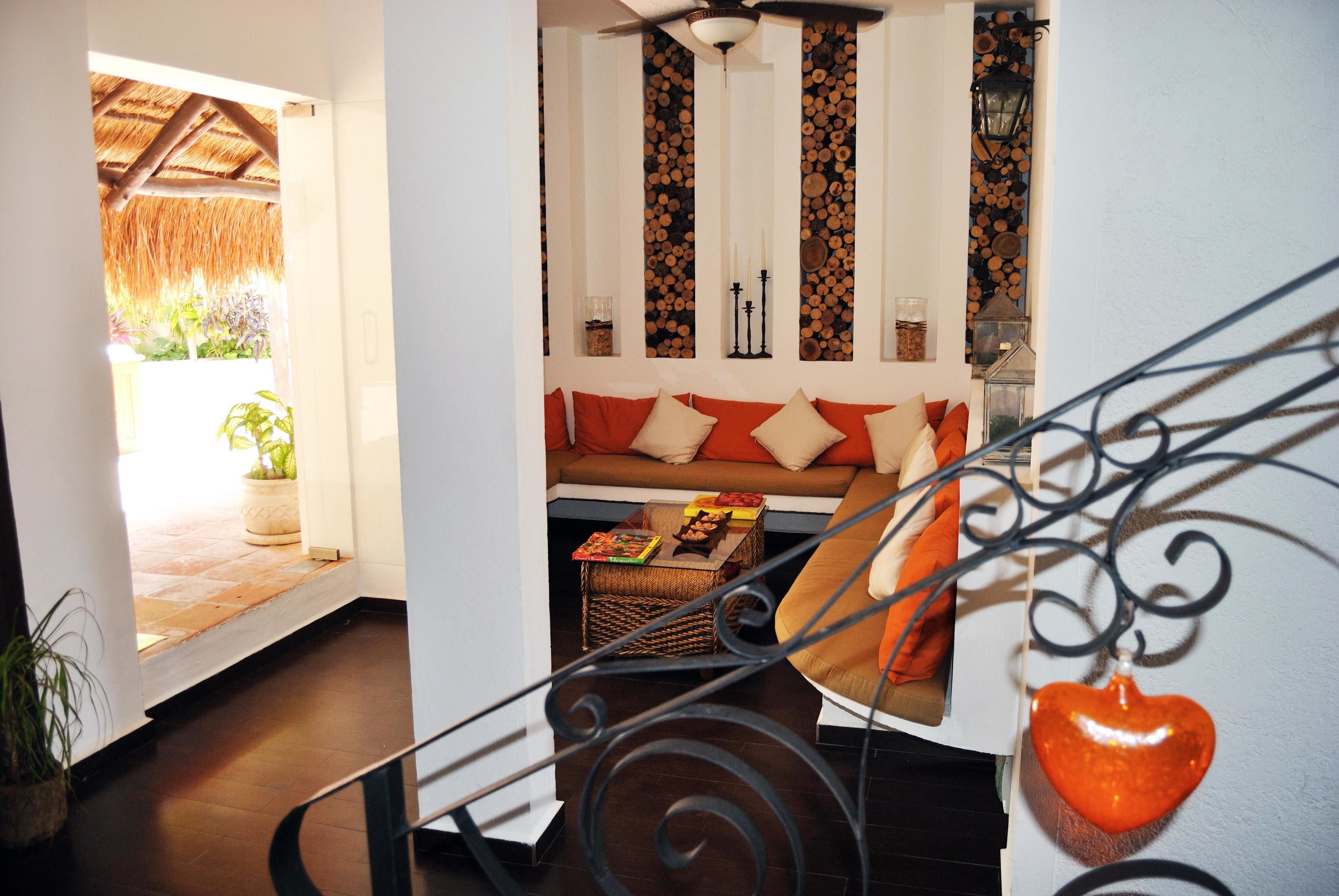 A staircase with a metal railing, a heart-shaped ornament, and a sofa with orange cushions.