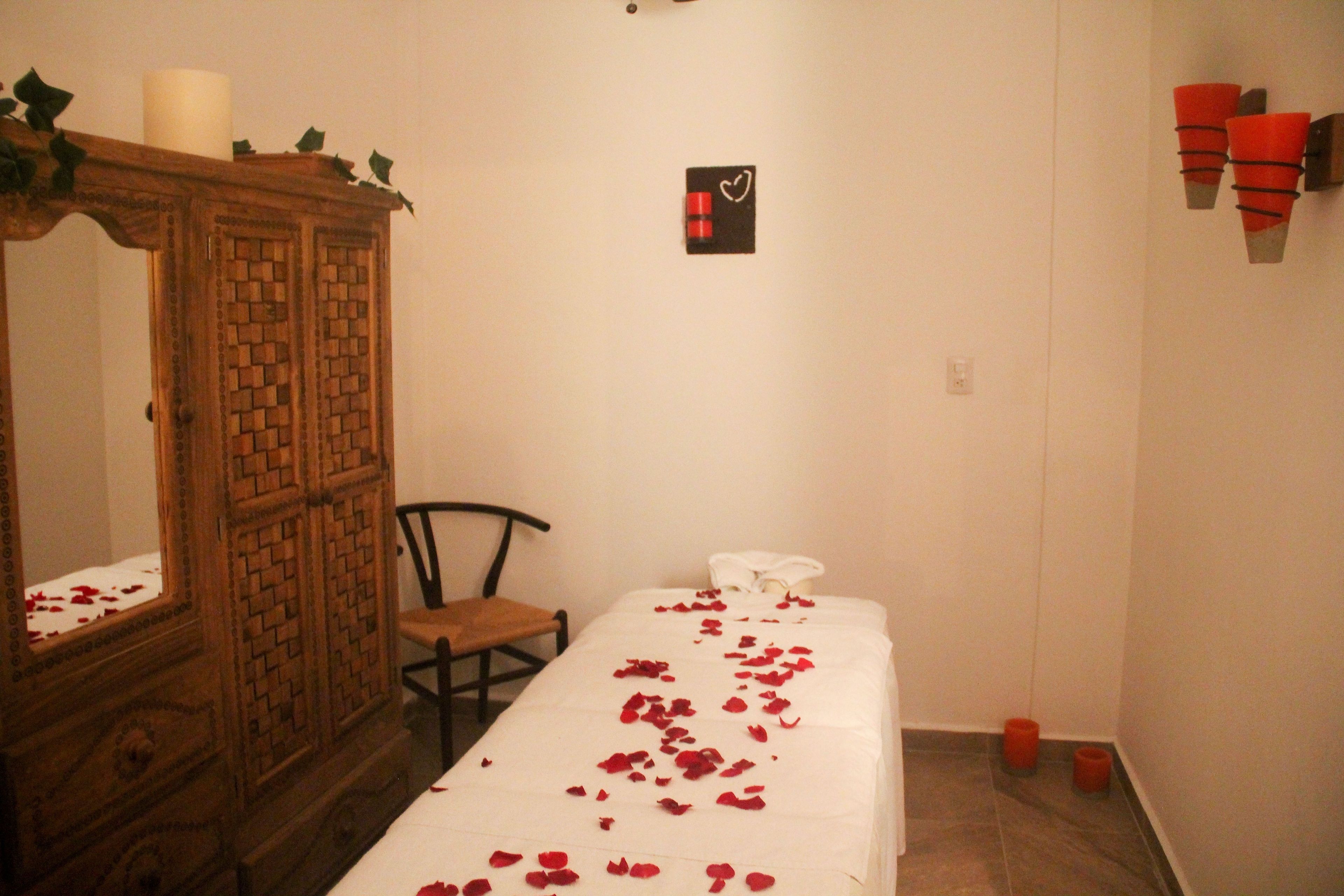 Una habitación con una cama, un armario de madera, una silla y una lámpara fijada a la pared.