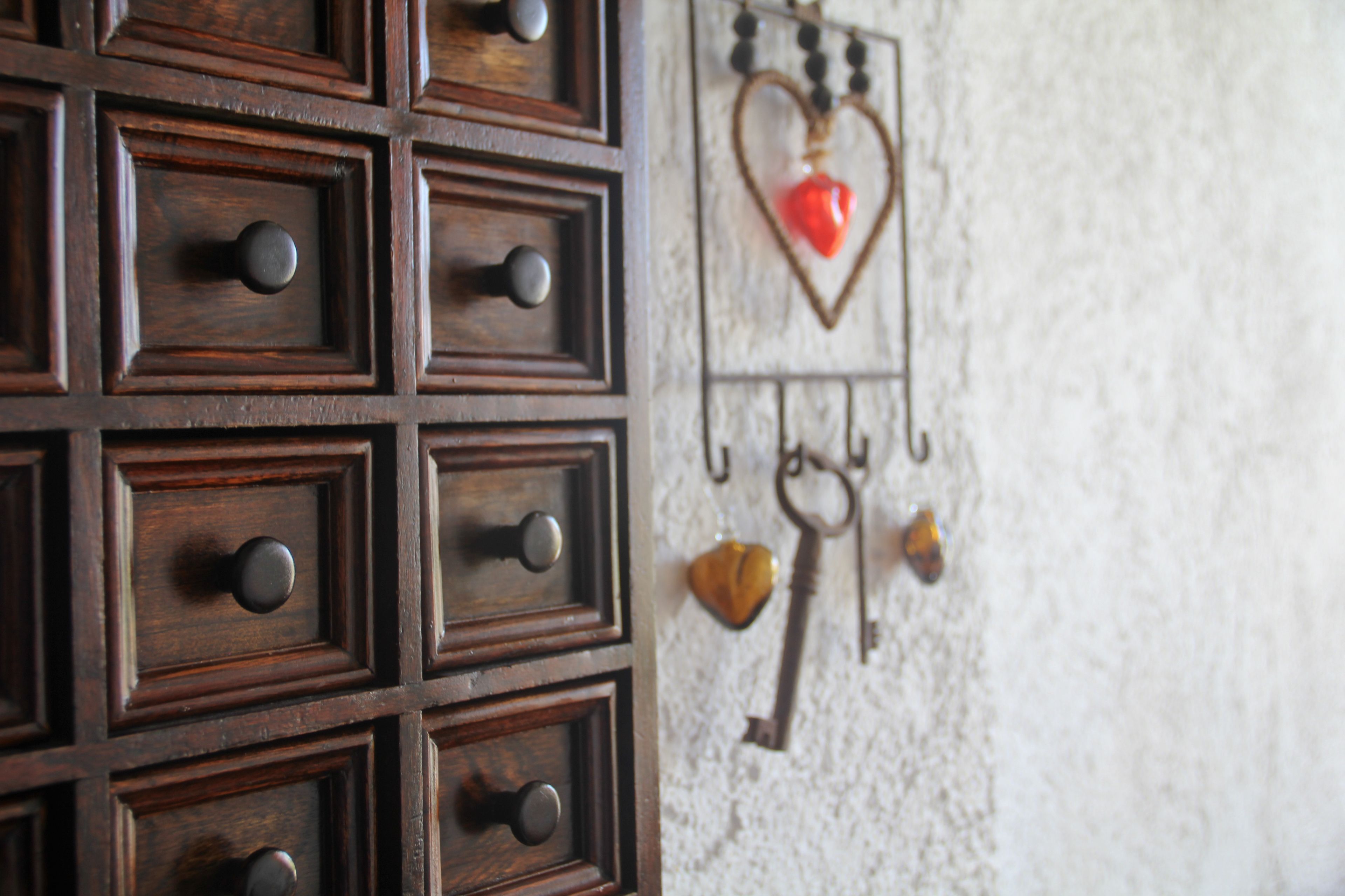 Una pared con varios cajones de madera y un atril con forma de corazón para llaves.