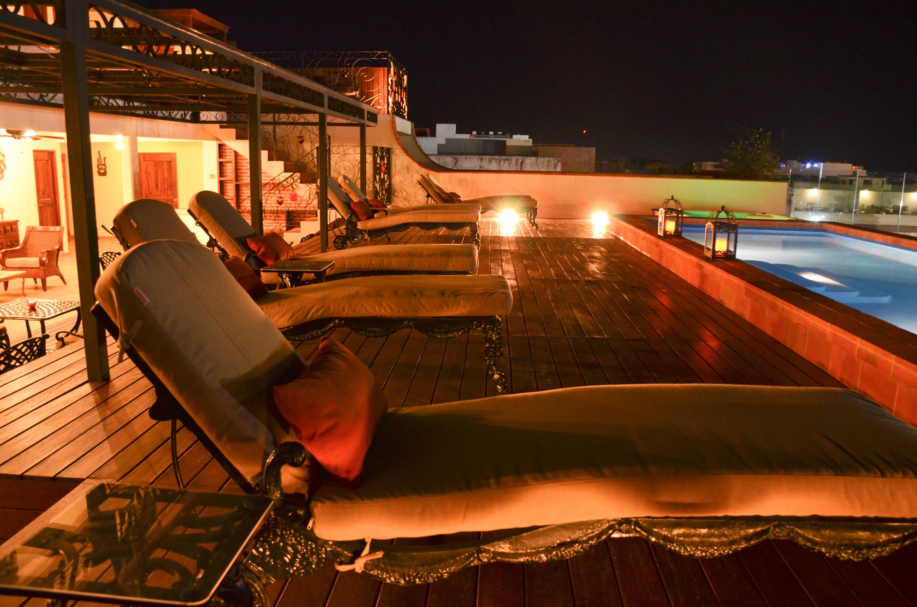 A rooftop lounge area with sun loungers and a pool.