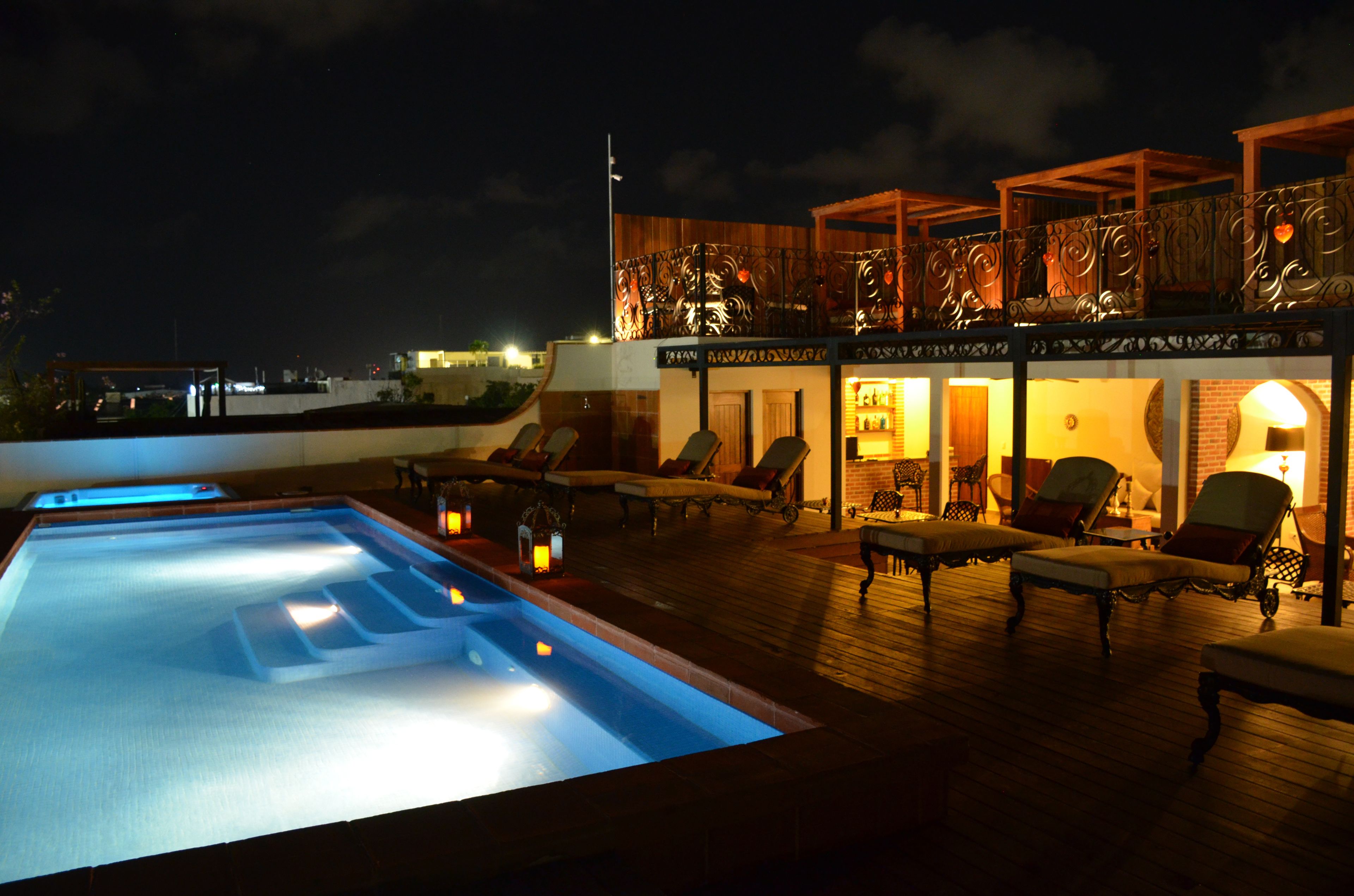 A rooftop pool area with lounge chairs and a bar.