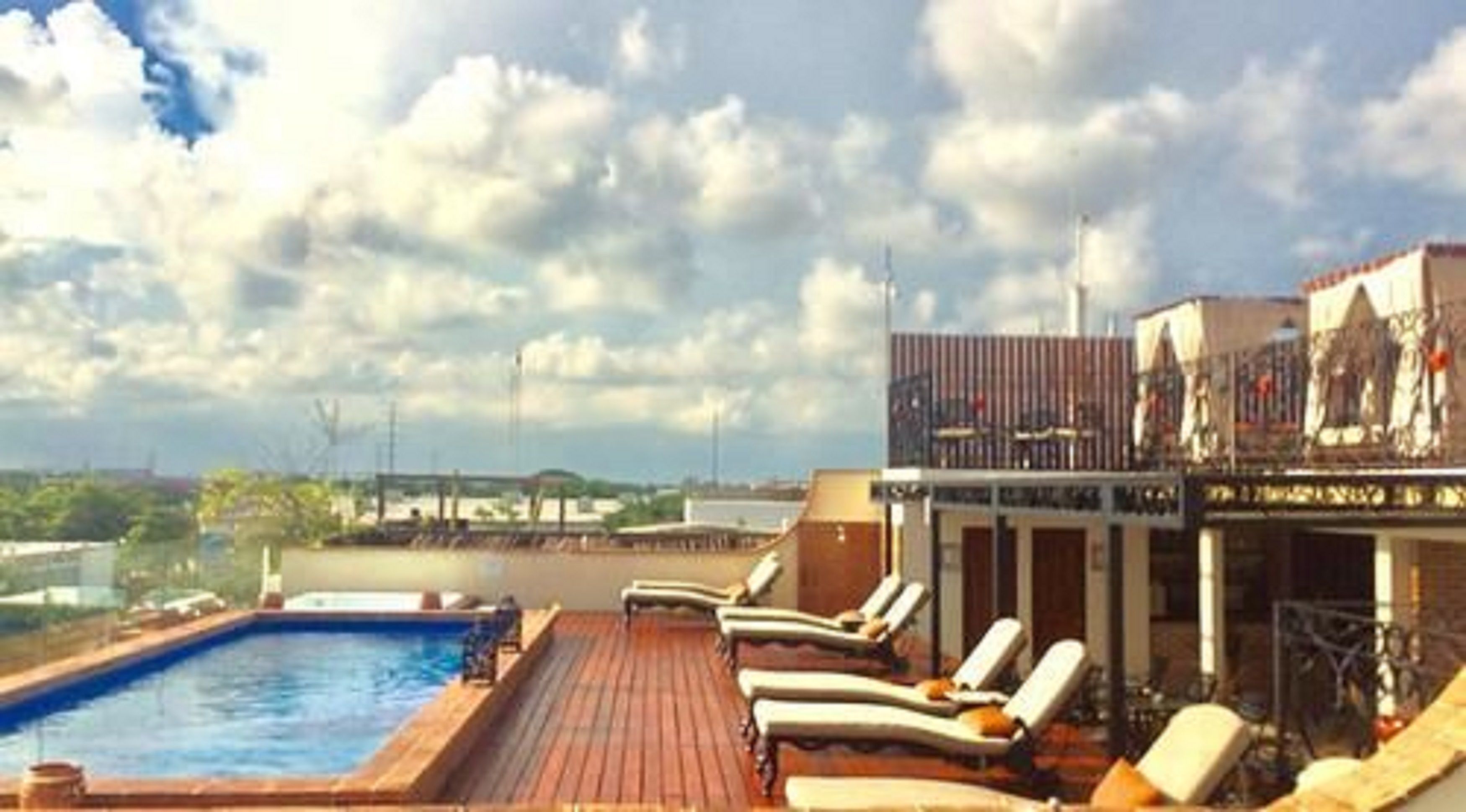 Zona de piscina en la azotea con sillas de descanso y vistas al horizonte de la ciudad.