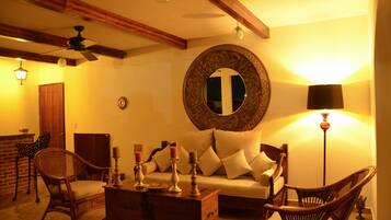 A cozy living room with a sofa, two wicker chairs, a wooden coffee table, and a ceiling fan.