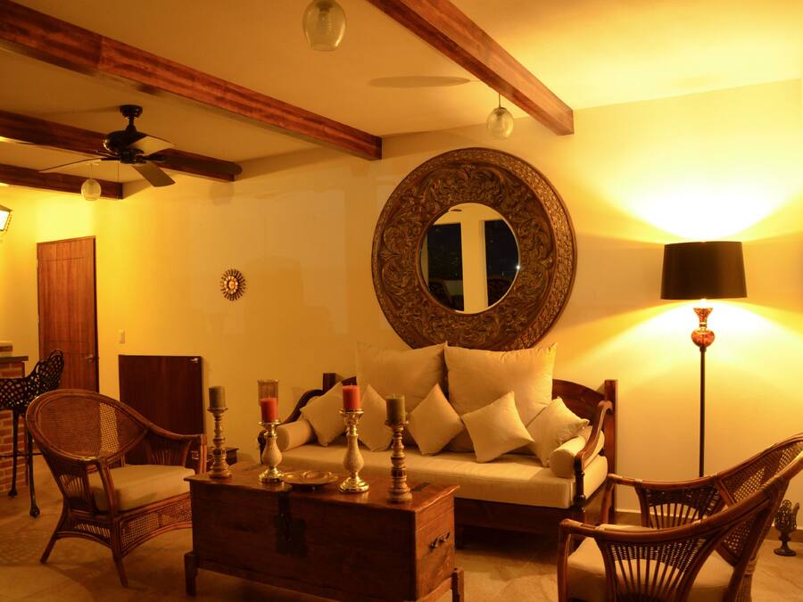 A cozy living room with a sofa, two wicker chairs, a wooden coffee table, and a ceiling fan.