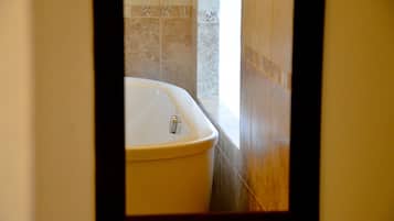 A bathroom with a white bathtub, tiled walls, and a wooden floor.