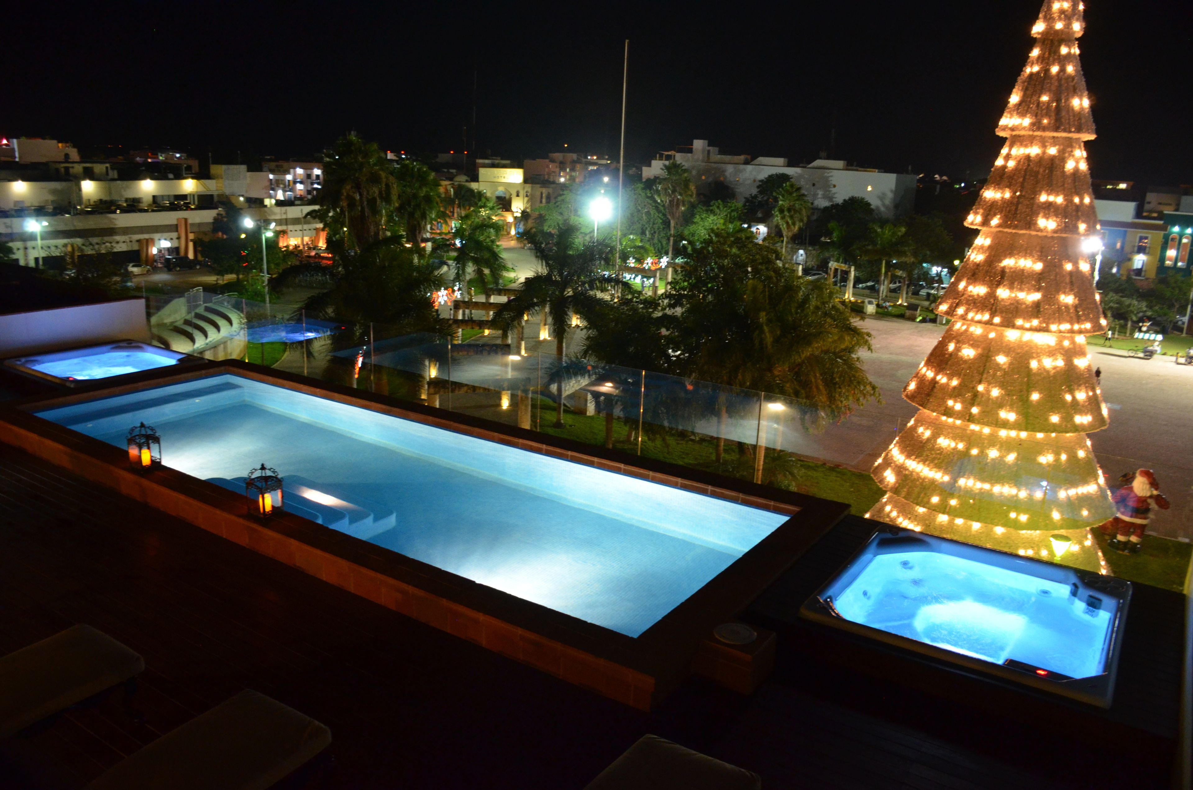 Ein Poolbereich auf dem Dach mit zwei Whirlpools und einer großen, beleuchteten Weihnachtstanne.