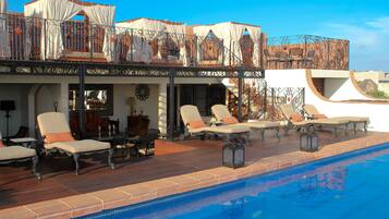 A poolside area with lounge chairs and a covered seating area.