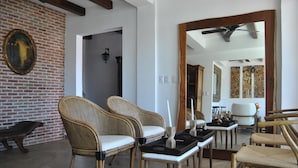 Amplia sala de estar con muebles de mimbre, pared de ladrillo y ventilador de techo.