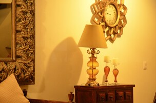 Une pièce avec un meuble en bois, une lampe, une horloge murale et un miroir.