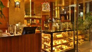 Vitrina de forn amb pastissos, una màquina de cafè i una caixa registradora.