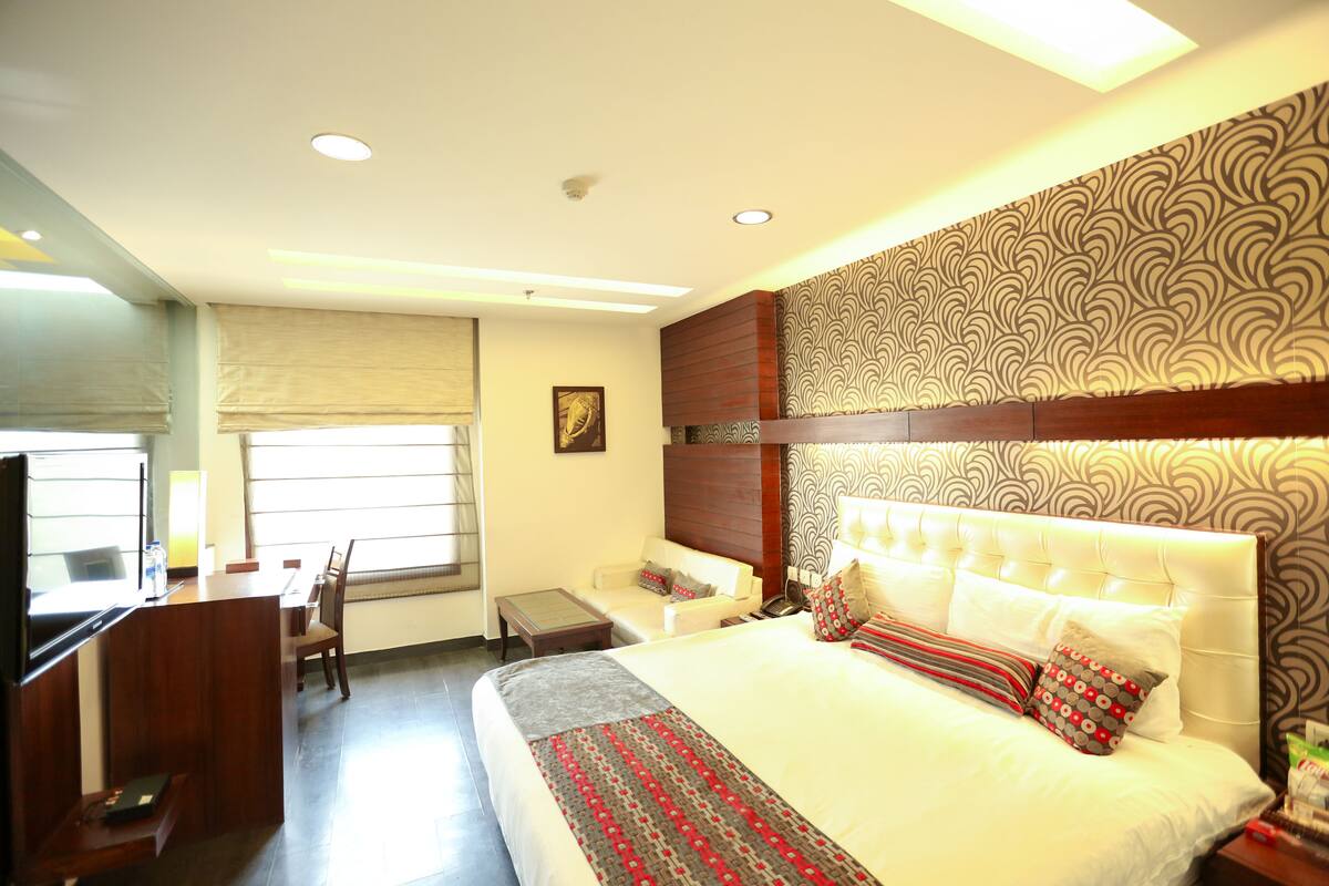 A hotel room with a bed, a desk, a chair, and a television.