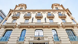 Un edificio histórico con detalles arquitectónicos ornamentales, varios balcones y grandes ventanales.