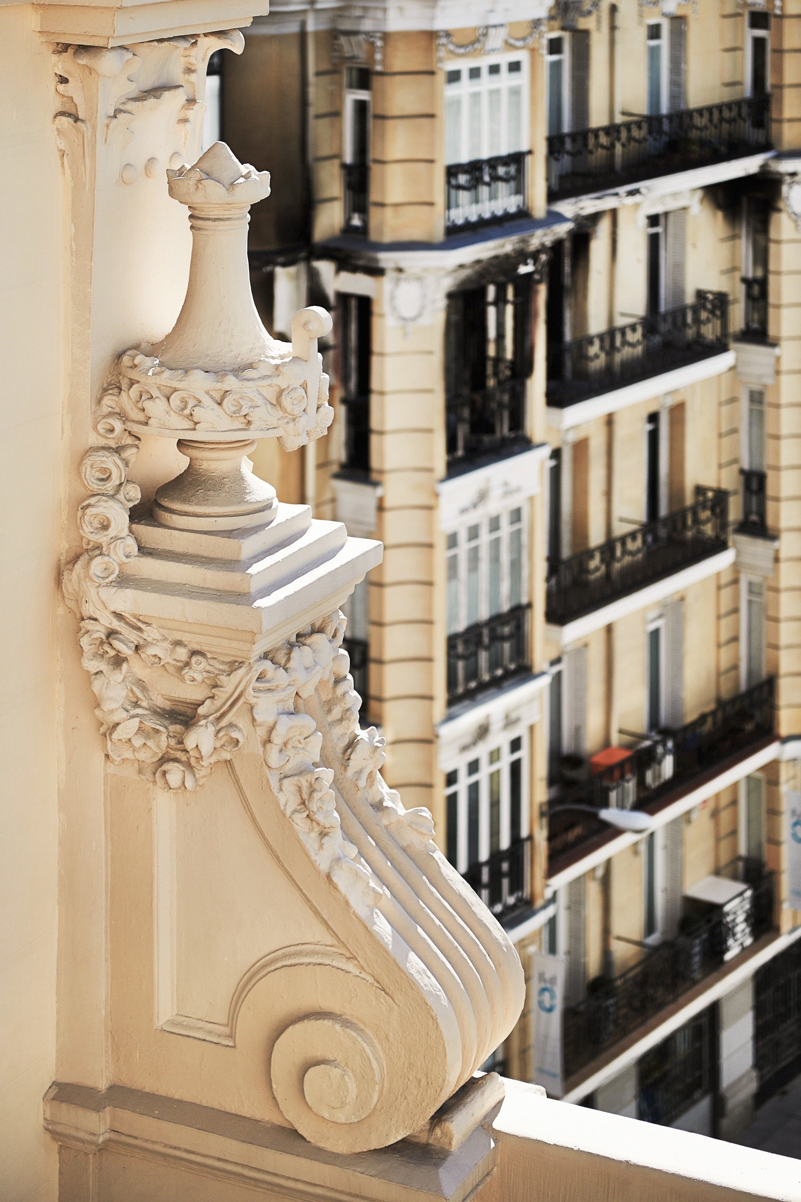 A detailed architectural column with ornate carvings, part of a building with multiple balconies and windows.