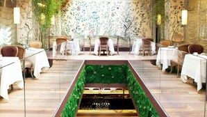 Un restaurante con techo de vidrio, jardines verticales verdes y una zona de bar central.
