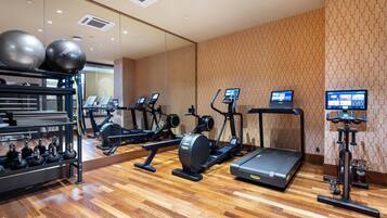 A gym with treadmills, elliptical machines, and free weights.