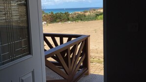 Una porta que dona a un balcó amb vistes a la platja i l'oceà.