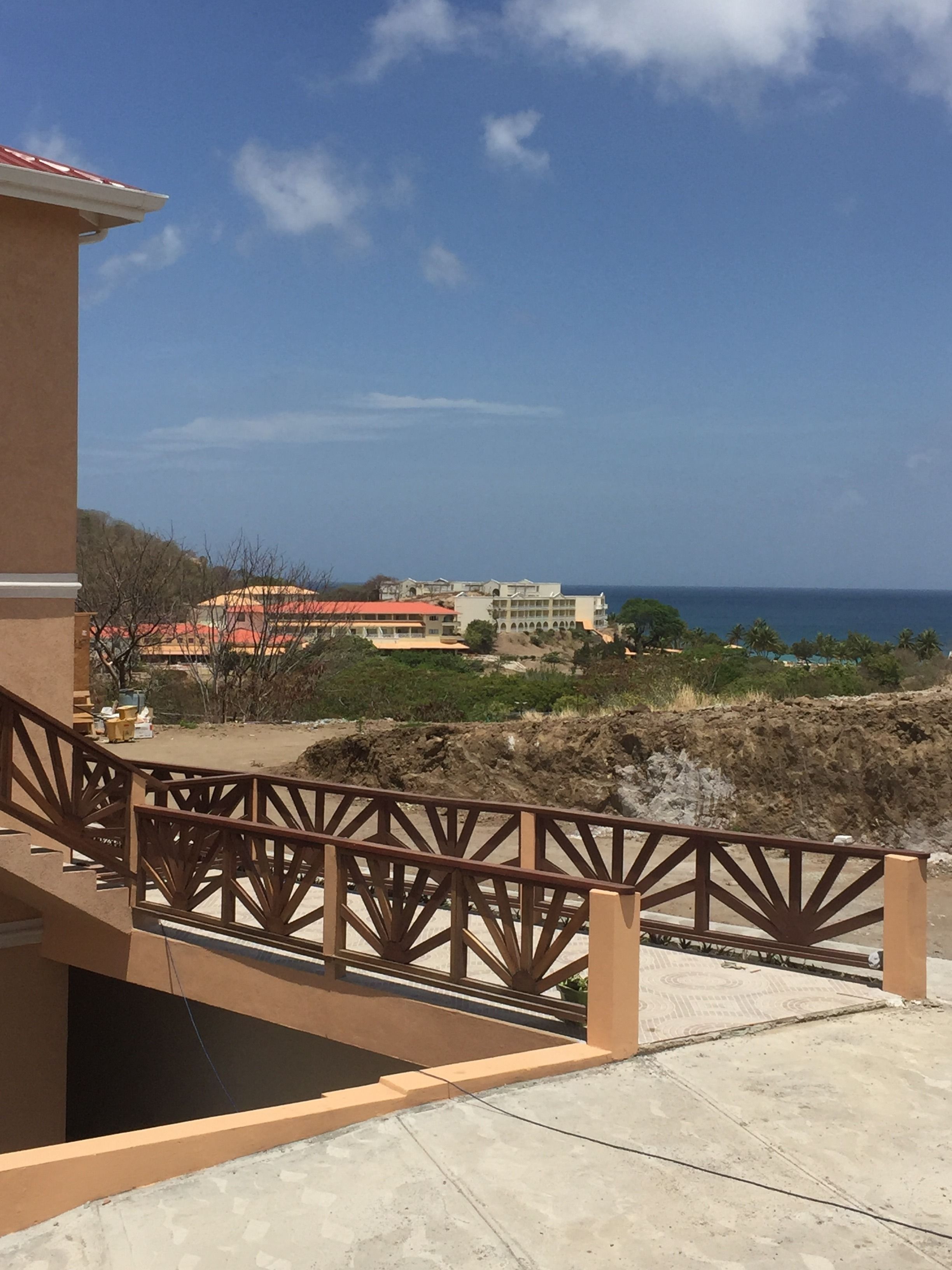 A balcony with a view of a coastal area, including buildings and the sea.
