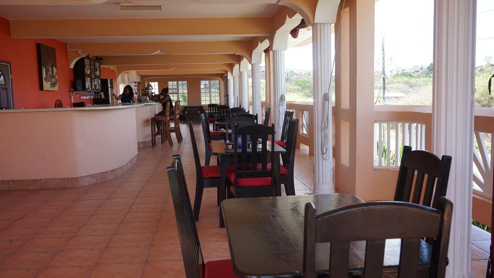 A covered outdoor dining area with a counter and chairs.