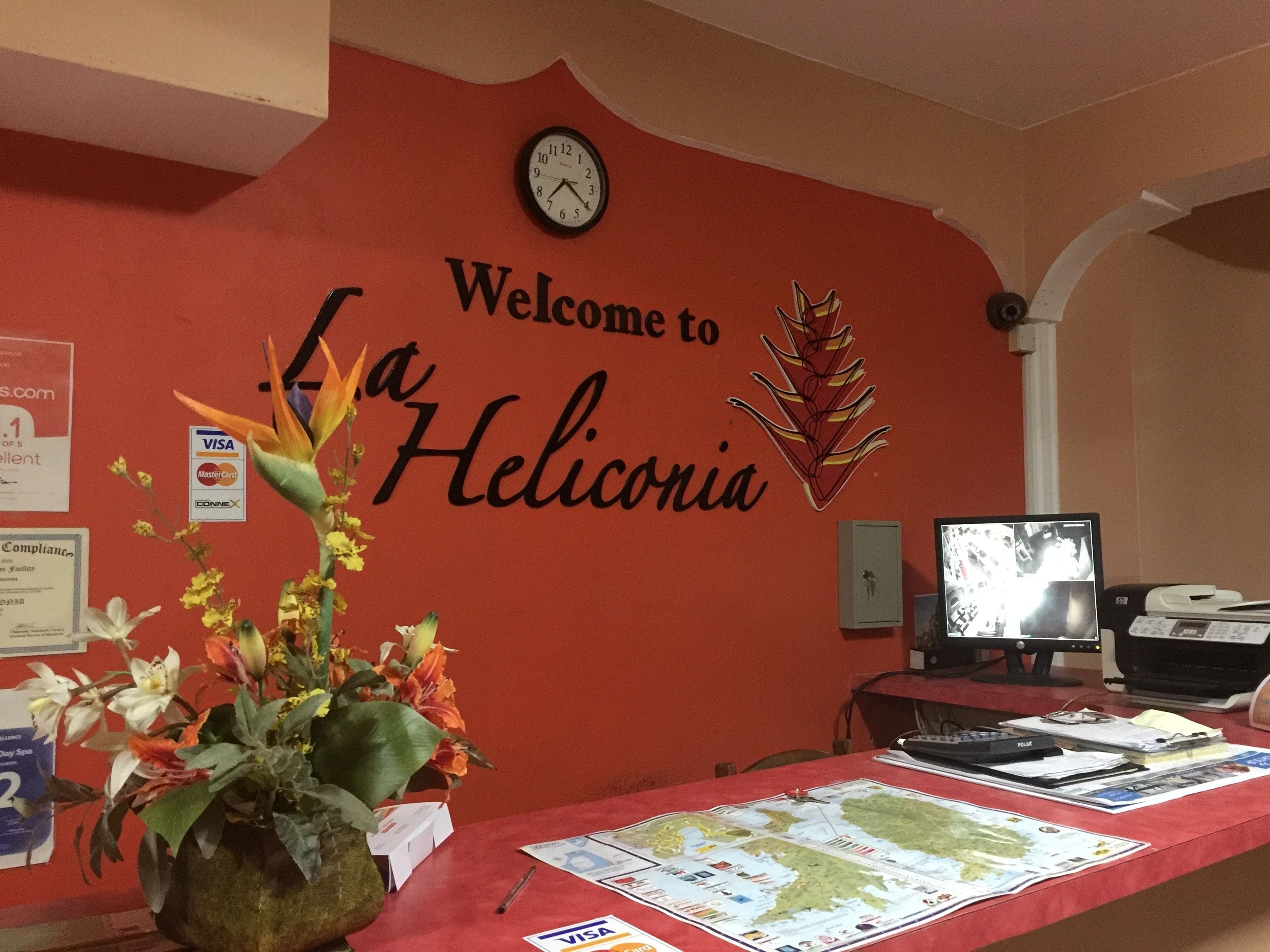 A reception desk with a red wall, a clock, and a welcome sign.