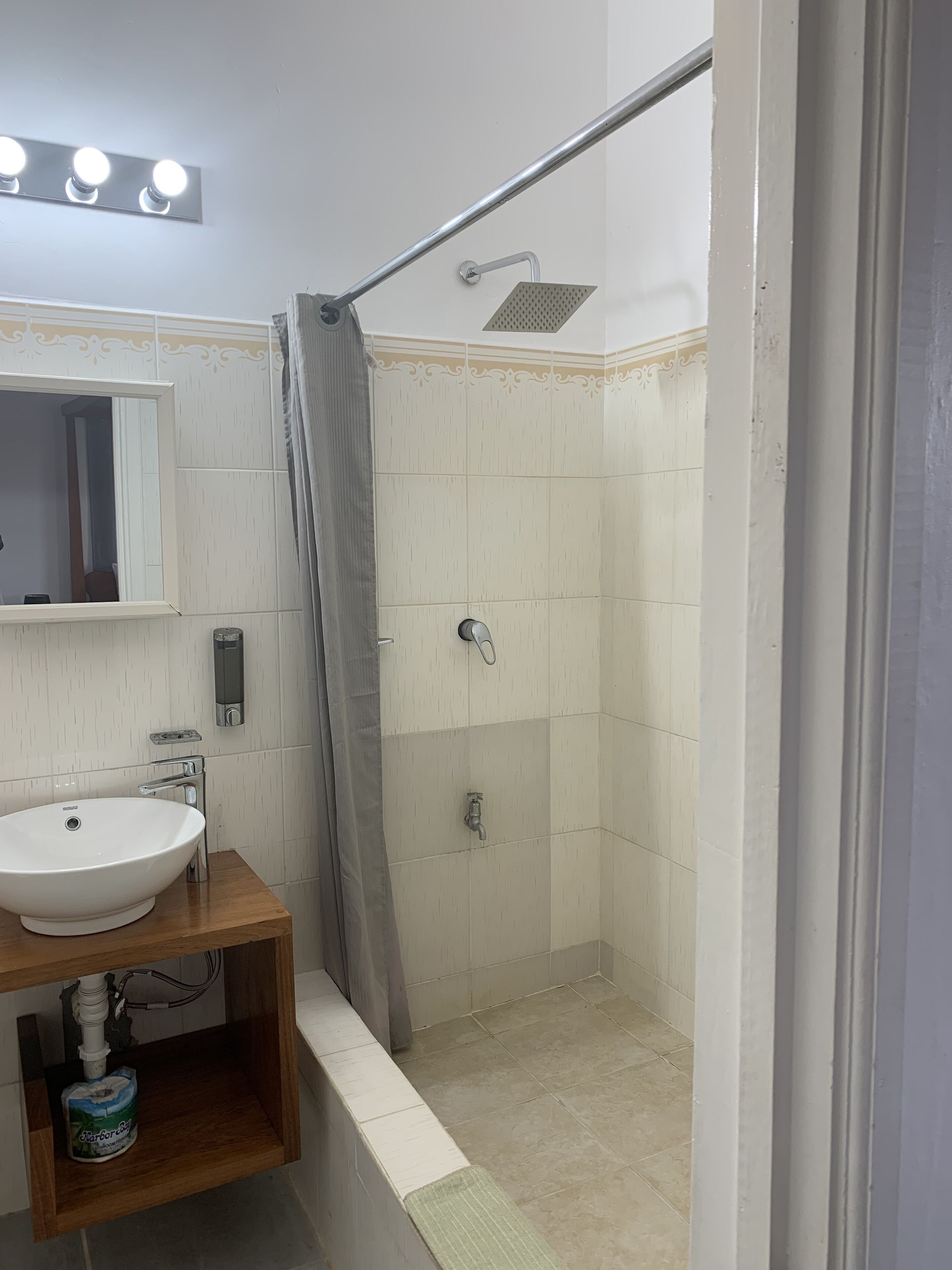 A bathroom with a sink, mirror, shower, and a towel rack.