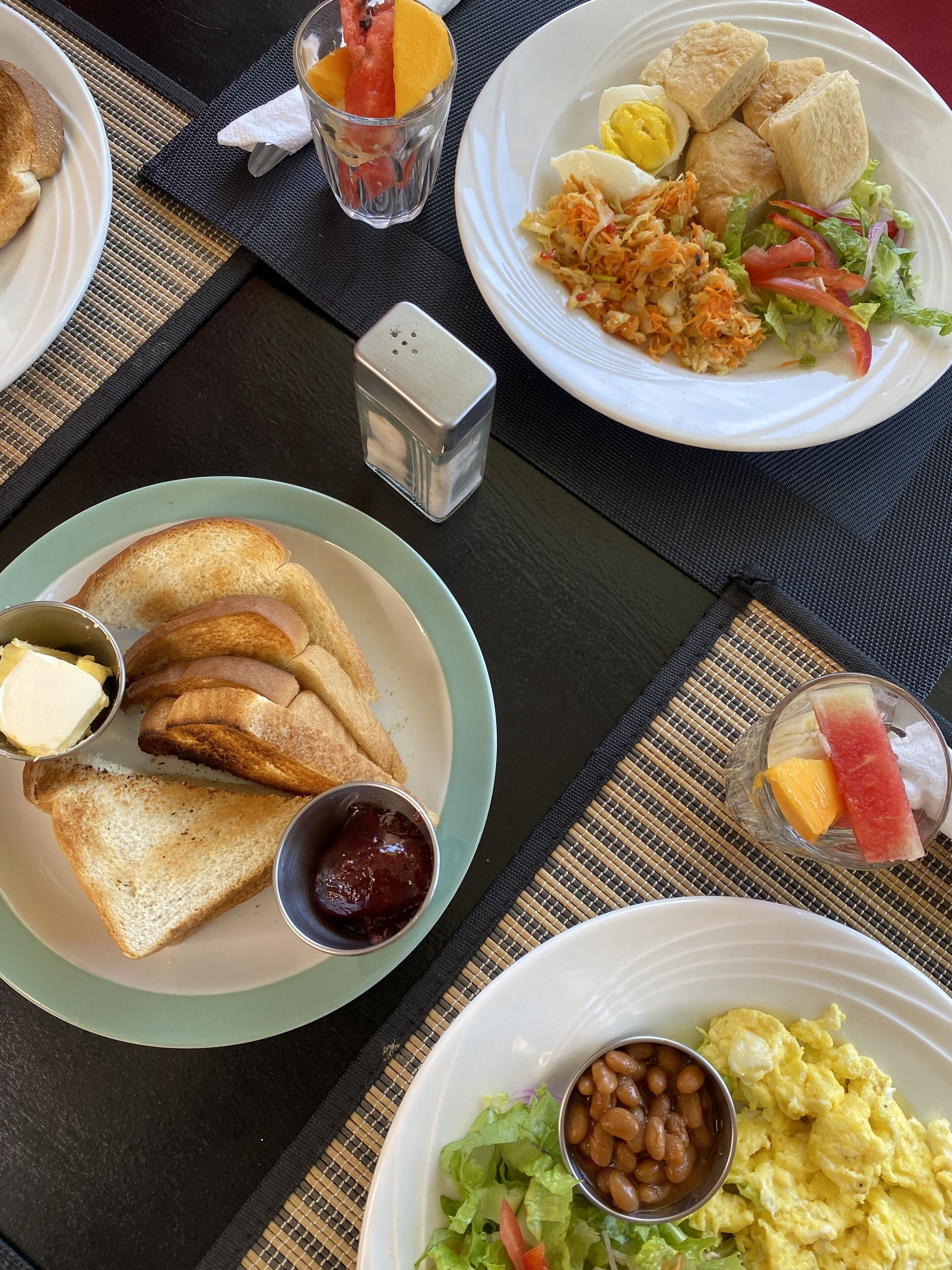 A table with breakfast plates containing toast, eggs, and salad.