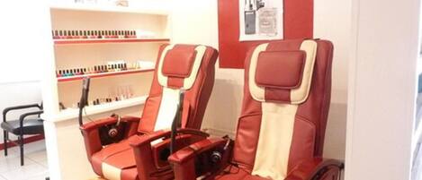 A massage chair with a footrest and a shelf with various products in the background.