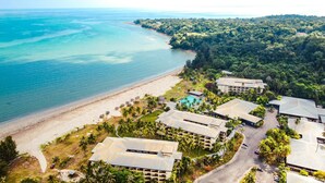 An aerial view of a resort with multiple buildings, a beach, and a pool.