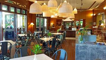 Un restaurant doté de nombreuses tables et chaises, de luminaires suspendus et d’un ventilateur de plafond.
