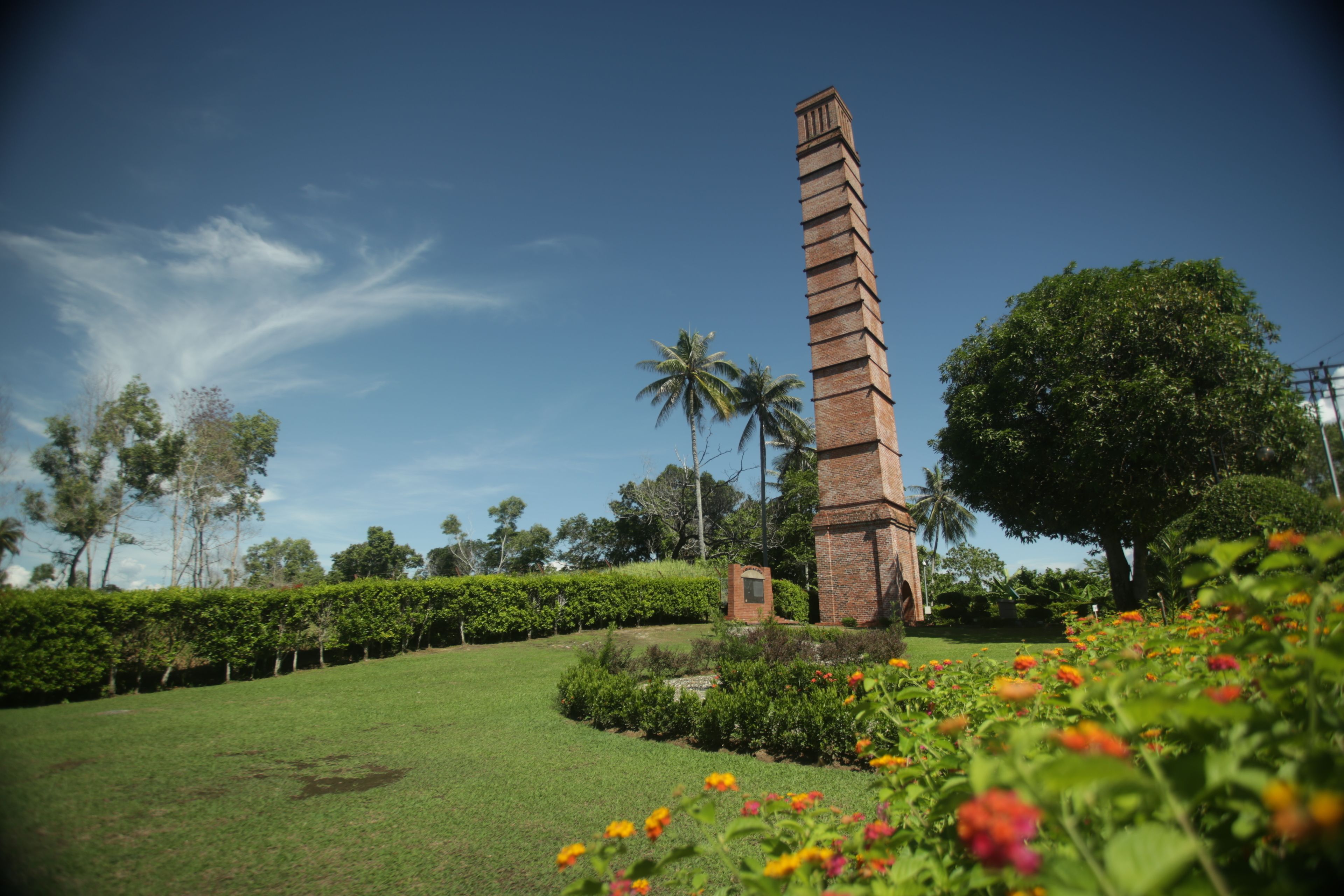 A tall brick monument in a landscaped garden with a clear sky.