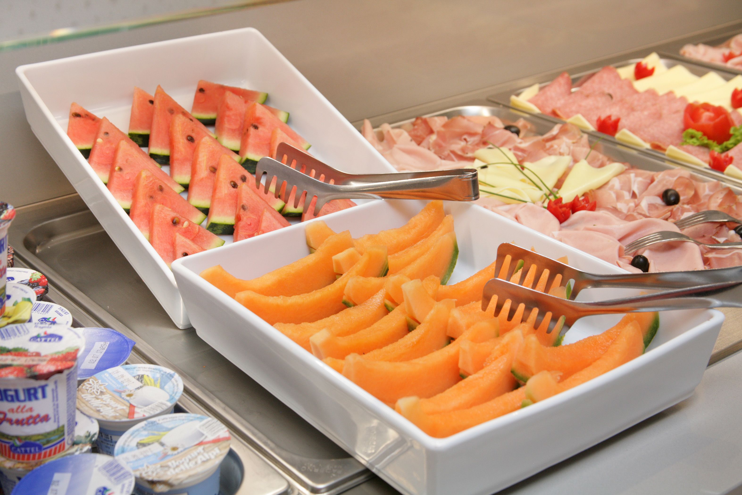 A buffet with various food items including watermelon, cantaloupe, cheese, and meats.