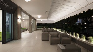 Un moderno vestíbulo de hotel con un área de descanso, una recepción y vistas a la calle.