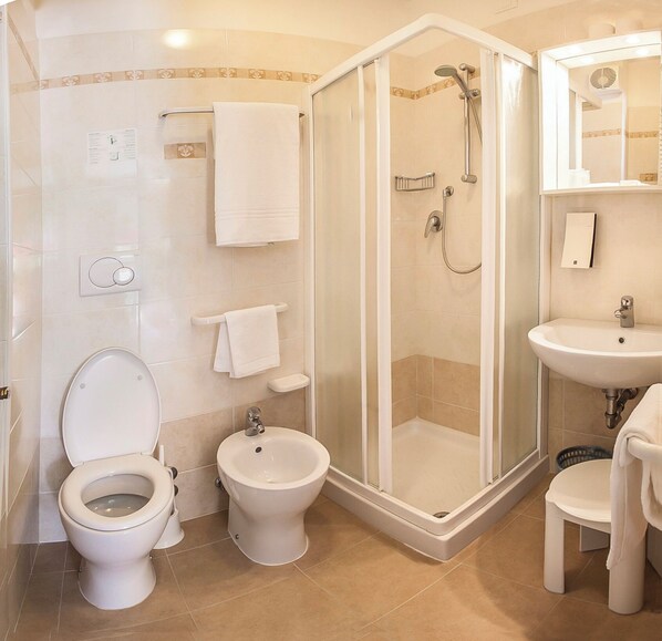 Un baño con inodoro, bidé, ducha y lavamanos.