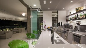 Cocina moderna con una isla central, zona de bar y asientos con sillas verdes.
